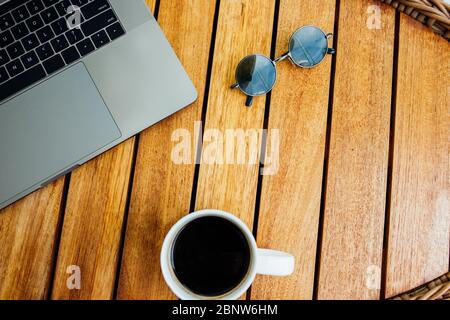 Flacher Arbeitsraum für die Arbeit an einem Laptop, ein brauner Holztisch mit einer Tasse Kaffee. Konzept für Freiberufler. Remote-Arbeit. Ort kopieren Stockfoto