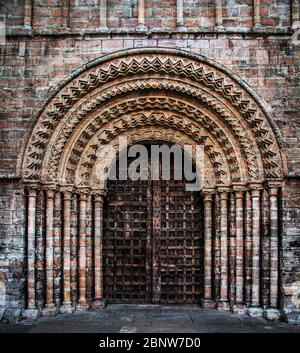 Ein gotischer Eingang zu einer Kirche oder Kathedrale mit schwerer Holztür und verzierten Steinschnitzereien mit Bögen und Säulen Stockfoto