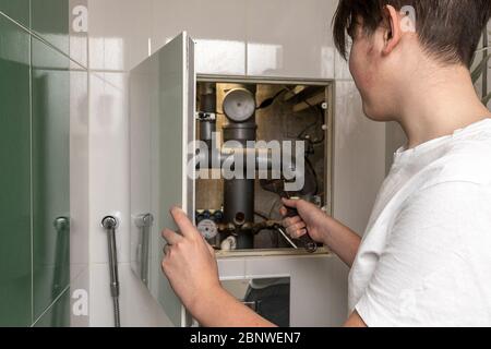 Master Reparatur Sanitär, Reparatur. Sanitär-Schrank. Wasserzähler, Kollektor Wasserdrucksensor Stockfoto