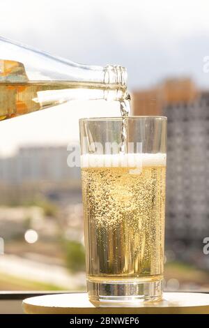 In ein Glas wird Mineralwasser gegossen, in einem Glas sprudelnde Blasen Stockfoto