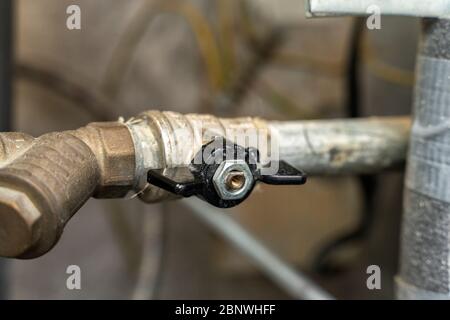 Sanitär-Schrank. Schalten Sie warmes oder kaltes Wasser. Nahaufnahme eines Wasserabsperrhahns. Rauer Wasserfilter Stockfoto