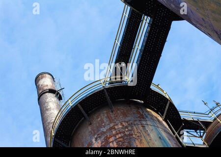 Hochöfen und Schornstein mit Gehwegen als Teil einer verlassenen alten industriellen Stahlmühle Website, von unten gesehen, blauer Himmel kopieren Raum, hor Stockfoto