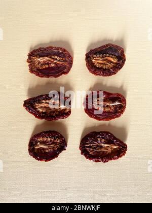 Getrocknete oder getrocknete Tomatenhälften, Draufsicht, verschiedene Formen und Größen, Samen nach oben. Beige Hintergrund, natürliche Farben Stockfoto