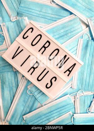 Blaue Gesichtsmasken mit einer weißen Leuchtbox, die Coronavirus angibt Stockfoto