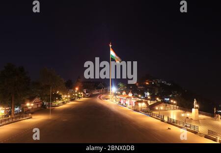 Schöne ruhige Landschaft der Mall Road von Shimla in der Nacht. Die indische Flagge flattert herrlich im Wind, während ein Hund friedlich auf dem Ro sitzt Stockfoto