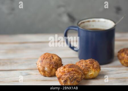 Blue Cup Kaffee mit heißen hausgemachten Kuchen auf dem Küchentisch. Home Frühstück Konzept. Muffins handgemacht. Selektiver Fokus Stockfoto