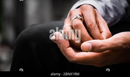 Nahaufnahme einer Hand Halten Malana Cream Haschisch auf der Spitze des Zeigefingers beim Zerkleinern, ein roter Rubinring ist auf der anderen Seite, 5K Stockfoto