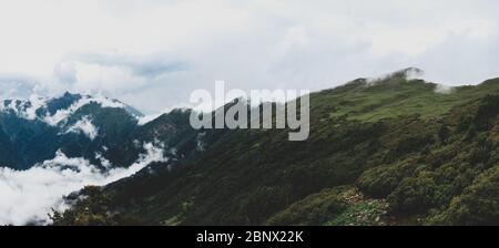 Vintage matt Stil Ultra HD 8K Ultra-Wide Panorama der riesigen Berge von Chandarkhani, Indien bedeckt mit Wolken, die winzig im Vergleich zu den breiten erscheinen Stockfoto