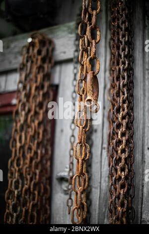 Rostige Eisenketten hängen von der Außenwand einer Scheune Stockfoto