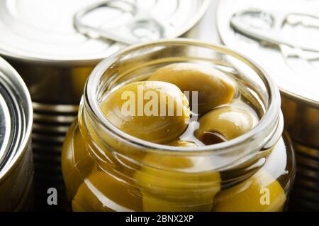 Grüne Oliven in der Dose in einem gerade geöffneten Glas. Nicht verderbliche Lebensmittel Stockfoto