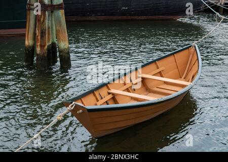 Kleines Ruderboot neben einem größeren Segelschiff und Delfinpier, horizontaler Aspekt Stockfoto