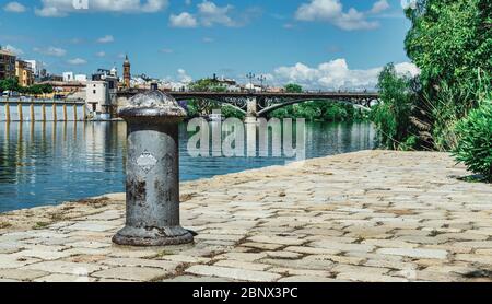 Selektiver Fokus auf einen Poller mit Triana-Brücke im Hintergrund während der Coronavirus-Pandemie in Sevilla. Guadalquivir r Stockfoto