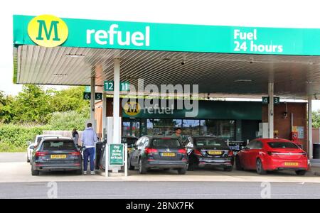 Autos warten an einer Morrisons-Tankstelle auf Benzin, die bleifreies Benzin mit 99,7 Pence pro Liter verkauft.das erste Mal seit 2016 wurde Benzin unter £1 pro Liter verkauft.der weltweite Ölmarktcrash, ausgelöst durch die Sperrung des Coronavirus, hat den Rohölpreis auf ein nahezu 20-Jahres-tief abgeflaut. Jetzt, angeführt von britischen Supermarket-Ketten, ist bleifreies Benzin jetzt auf Verkauf im ganzen Land bei unter £1 pro Liter. Stockfoto