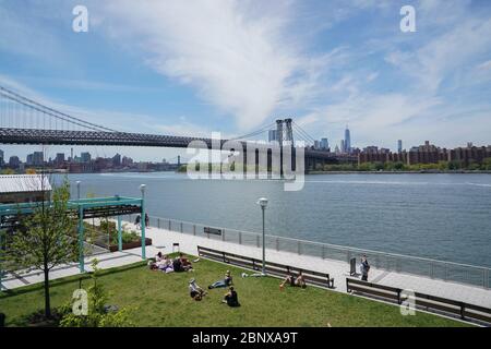 New York, NY, USA. Mai 2020. Während der COVID-19-Pandemie am 16. Mai 2020 in New York sitzen die Menschen im Domino Park im Borough of Brooklyn auf dem Gras. Kredit: Bryan Smith/ZUMA Wire/Alamy Live News Stockfoto