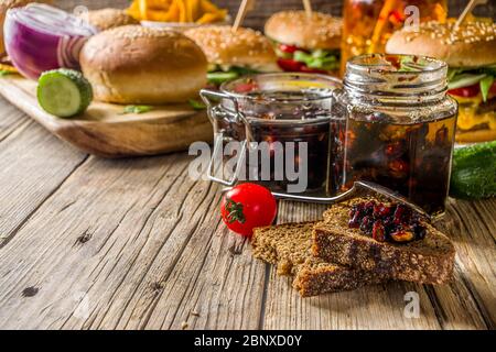 Hausgemachte Speck Marmelade in Gläsern, mit Brot und Burger Stockfoto