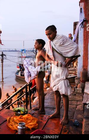 Indien, Varanasi - Bundesstaat Uttar Pradesh, 31. Juli 2013. Zwei Jungen trocknen sich und ziehen ihre Kleider nach dem Morgenbad im Ganges an - dem heiligen Fluss Indiens. Stockfoto