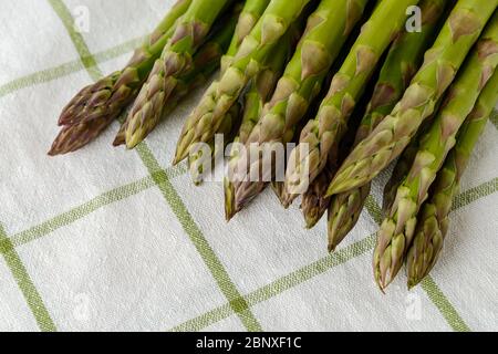 Ein Bund frischer roher grüner Spargelstängel auf einem weißen Küchentuch. Zutat für gesunde Ernährung, vegetarische und Rohkost Ernährung. Nahaufnahme. Stockfoto