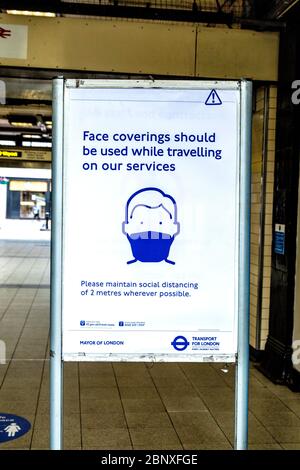 16. Mai 2020 London, Großbritannien - Schild, das die Menschen daran erinnert, Gesichtsmasken zu verwenden, während sie auf öffentlichen Verkehrsmitteln an der U-Bahnstation Embankment unterwegs sind, da die strengen Maßnahmen zur Sperrung der Coronavirus-Pandemie gelockert werden Stockfoto