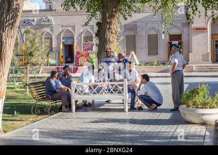 BUCHARA, USBEKISTAN - 27. AUGUST 2016: Einige Männer spielen Karten im zentralen Garten Bucharas in Usbekistan Stockfoto