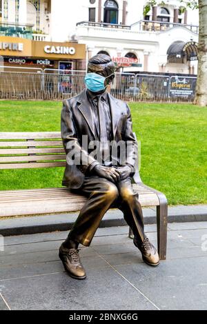 16 May 2020 London, UK - Statue von Mr Bean auf einer Bank sitzend, die während der Sperrung der Coronavirus-Pandemie eine schützende Gesichtsmaske trägt Stockfoto