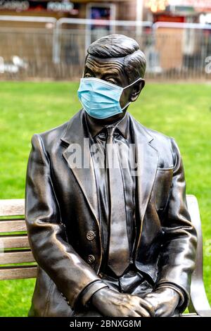 16 May 2020 London, UK - Statue von Mr Bean auf einer Bank sitzend, die während der Sperrung der Coronavirus-Pandemie eine schützende Gesichtsmaske trägt Stockfoto