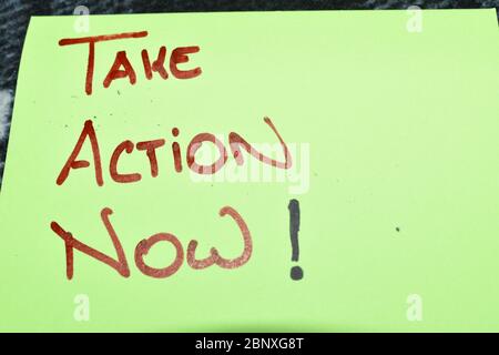 Nahaufnahme einer fluoreszierenden grünen Farbe Post-it Note.The Worte "Take Action Now" sind Hand auf Großbuchstaben in roten Marker Stift geschrieben. Stockfoto