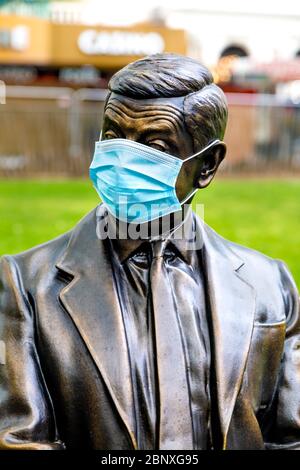 16 May 2020 London, UK - Statue von Mr Bean auf einer Bank sitzend, die während der Sperrung der Coronavirus-Pandemie eine schützende Gesichtsmaske trägt Stockfoto