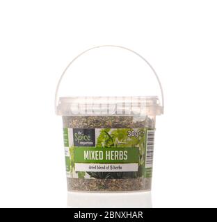 Plastikwanne aus getrockneten gehackten gemischten Kräutern aus dem Gewürz Emporium isoliert vor einem weißen Hintergrund mit einer Reflexion. Stockfoto