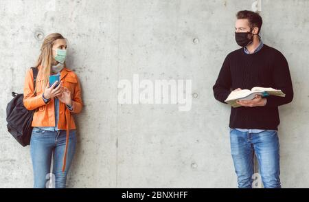 Zwei Studenten stehen in sozialer Distanz und tragen eine Gesichtsmaske Stockfoto