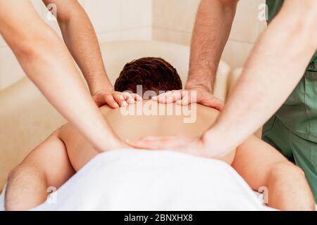 Junger Mann erhält Rückenmassage im Spa-Salon. Stockfoto