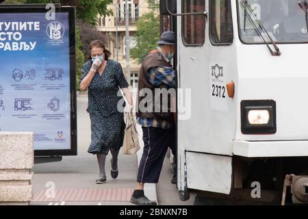 Belgrad, Serbien - 12. Mai 2020: Ältere Menschen, die Gesichtsmaske und Handschuhe tragen, steigen in die öffentlichen Verkehrsmittel Stockfoto