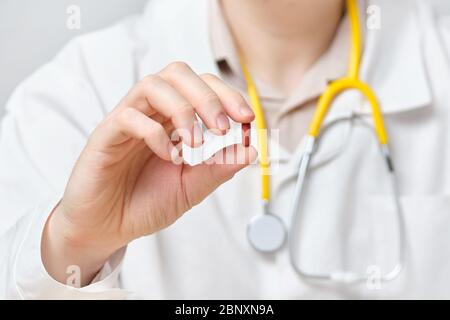 Ein männlicher Arzt hält ein Medikament in Form einer Pille. Nahaufnahme. Stockfoto
