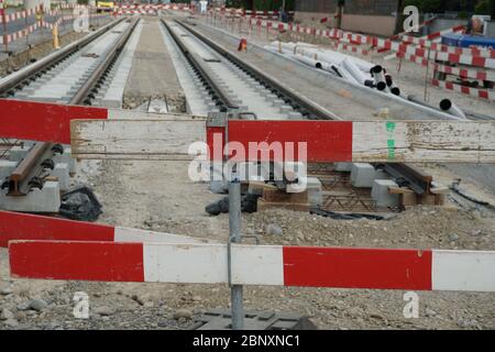 Bau einer Straßenbahn, Einbettung von Metallschienen in einen Betonsockel mit einer Barrieresteele im Vordergrund aus Sicherheitsgründen. Stockfoto