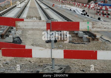 Bau einer Straßenbahn, Einbettung von Metallschienen in einen Betonsockel mit einer Barrieresteele im Vordergrund aus Sicherheitsgründen. Eine zivile eng Stockfoto