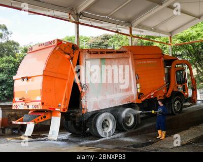 Medellin, Kolumbien, Oktober 15 2019: Ein Arbeiter reinigt mit Wasser und Schaum einen emvarias garbaje LKW bewegt durch Gas Abfallwirtschaft in Medellin C Stockfoto