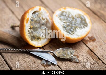 Schnittholz Passionsfrucht mit Messer und Löffel auf rostigen Holzhintergrund. Food-Fotografie Stockfoto