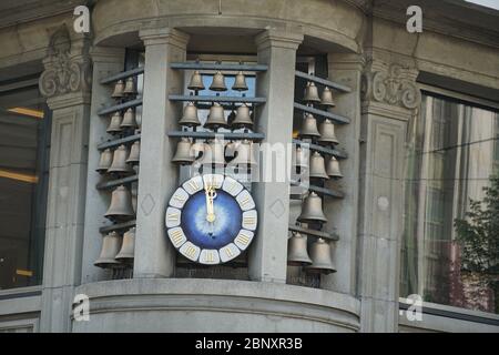 Glockenspiel in Zürich stehen Glocken verschiedener Größen rund um die Uhr an der Ecke eines historischen Gebäudes aus der Nähe. Die Glocken spielen eine Melodie. Stockfoto