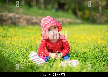 Kleines Mädchen spielt auf der Natur vor dem Hintergrund der grünen. Stockfoto