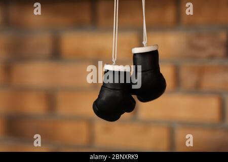 Kleine dekorative schwarze Boxhandschuhe. Boxhandschuhe hängen auf Nagel an Textur Wand mit Kopierraum für Text. Ruhestand concept.selective Schwerpunkt. Stockfoto