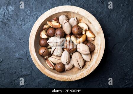 Getrocknete gemischte Nüsse in Holzschale Nahaufnahme. Macadamia, Pecan und Paranüsse mit Messer auf Holztisch. Makroaufnahmen in Studio. Stockfoto