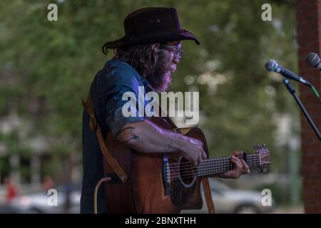 Bärtige Folksängerin beim Outdoor-Konzert. Singen und spielen akustische Gitarre. Stockfoto