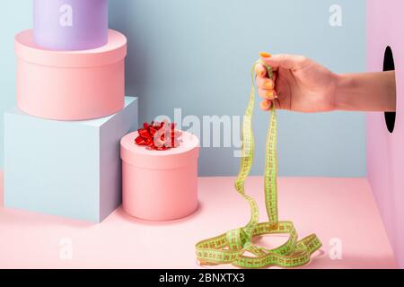 Hand hält ein Maßband auf blauem und rosa Hintergrund Stockfoto