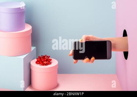 Hand hält ein Handy mit leerem Display auf blauem und rosa Hintergrund. Stockfoto