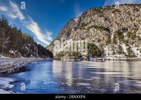 Winterlandschaft in der Lagune des Kurortes Panticosa mit den Bergen im Hintergrund mit Schnee aus den Pyrenäen, Huesca, Aragon, Spanien. Stockfoto