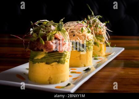 Traditionelle peruanische Gericht namens Causa aus Kartoffelpüree mit Aji Chili und Limettensaft und gefüllt mit Gemüse Mais, Erbsen, Karotten und Stockfoto