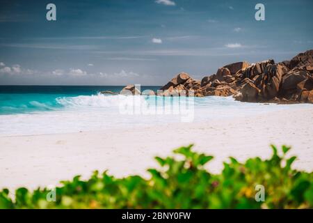 Schäumende Wellen und weißer Sandstrand am Petite Anse, La Digue auf den Seychellen Stockfoto