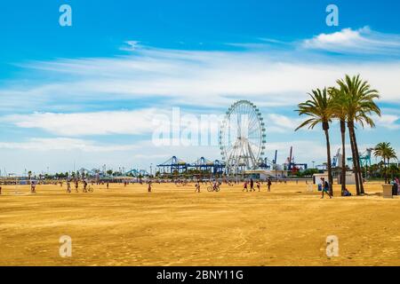 Valencia, Spanien: 14. Juni 2015 - Touristen und Einheimische gehen an den Strand, mit dem Riesenrad im Hintergrund Stockfoto