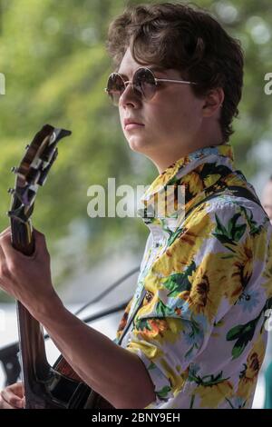 Teenager-Bassist in der Band, spielt bei einem Konzert draußen. Stockfoto