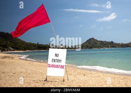 Quarantänekonzept, geschlossene Grenzen, Urlaubsstornierung. Tropischer Strand an einem sonnigen Tag ohne Menschen. Es gibt eine rote Flagge und ein Schild mit Nein Stockfoto