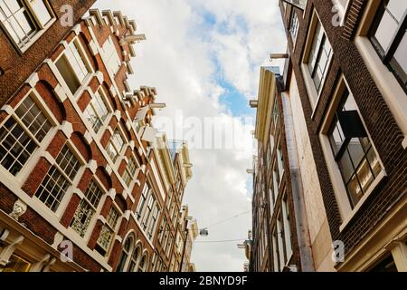 Gasse mit alten Häusern in niedriger Perspektive in Amsterdam, Niederlande Stockfoto